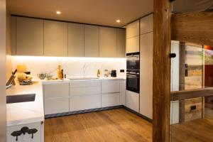 una cocina con armarios blancos y electrodomésticos negros en Chalet Noor - Chalets pour 12 Personnes 134 en Saint-Martin-de-Belleville