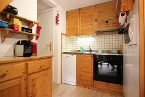 a kitchen with wooden cabinets and a black dishwasher at Résidence Les Avenieres - LES AVENIERES - AV30E MAE-4224 in Villarodin-Bourget +6 photos