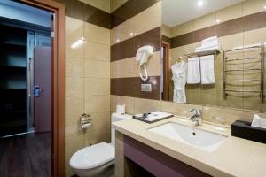 W łazience znajduje się umywalka, toaleta i lustro. w obiekcie Hotel SKY CENTR Krasnoyarsk w Krasnojarsku