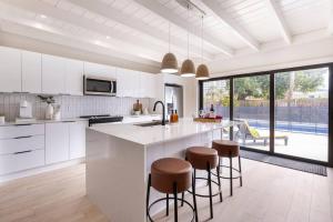 a kitchen with white cabinets and a large island with stools at Modern Beach Home, Family Friendly, Heated Pool in West Palm Beach