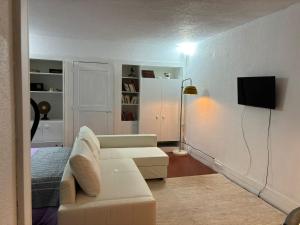a living room with a white couch and a tv at TROIAMAR in Troia