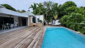 een huis met een zwembad en een houten terras bij Villa JELO - 2 Suites 2.5 Sdb Piscine & SPA* * * * in Saint Barthelemy