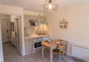a kitchen with a table and a small kitchen with a table and chairs at Résidence L'horizon - Studio pour 4 Personnes 584 in Les Orres