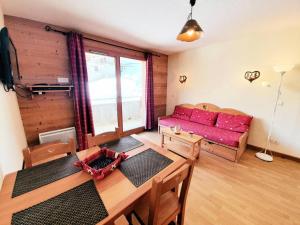 ein Wohnzimmer mit einem roten Sofa und einem Tisch in der Unterkunft Les Chalets Des Rennes - 2 Pièces pour 4 Personnes 744 in Vars