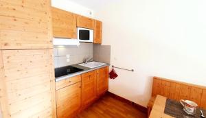 een keuken met houten kasten en een wastafel bij Les Chalets Des Rennes - 2 Pièces pour 4 Personnes 734 in Vars