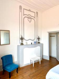 1 dormitorio con silla azul y espejo en Ermitage Saint Vincent B&B, en Vieille-Brioude