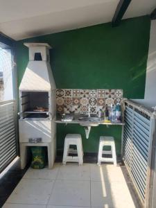 - une cuisine avec une cuisinière et deux tabourets dans l'établissement Casa 4 quartos paraiso santa efigênia reg residenc, à Belo Horizonte