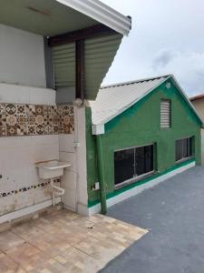 - un bâtiment vert et blanc avec une fenêtre et un lavabo dans l'établissement Casa 4 quartos paraiso santa efigênia reg residenc, à Belo Horizonte