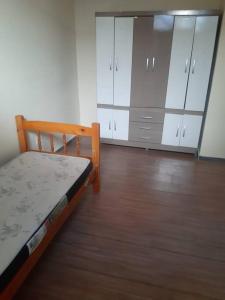 - une chambre avec un lit, des armoires blanches et du parquet dans l'établissement Casa 4 quartos paraiso santa efigênia reg residenc, à Belo Horizonte