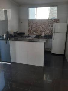  La cuisine est équipée de placards blancs et d'un réfrigérateur. dans l'établissement Casa 4 quartos paraiso santa efigênia reg residenc, à Belo Horizonte