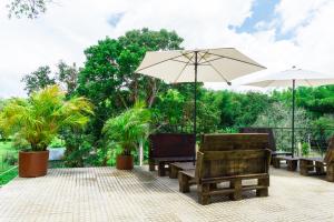 un patio con mesas, sillas y una sombrilla en Hermosa Finca Campestre Betania en Restrepo Valle, en Agua Mona