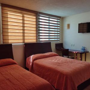Habitación de hotel con 2 camas y mesa en Hotel CR Tehuacan, en Tehuacán