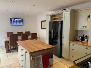 eine Küche mit einem Kühlschrank und einem Tisch darin in der Unterkunft Stable Cottage in Tettenhall