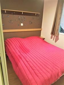 uma cama com um edredão vermelho num quarto em Mobil-home 4 pers. proche plage 69085 em Saint-Jean-de-Monts