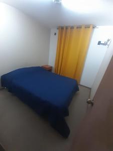 a bedroom with a blue bed and a yellow curtain at Departamento vallenar in Vallenar