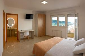 ブエウにあるApartamentos Costas de Bueuのベッドルーム1室(ベッド1台、デスク、窓付)