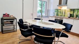 cocina con mesa blanca y sillas negras en 135m²-Apartment I max. 8 Gäste I Zentral I Küche I Balkon I Parken I WLAN, en Lünen