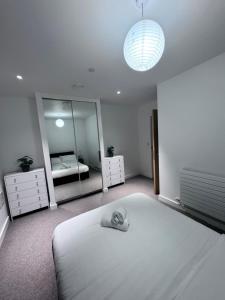 1 dormitorio con 1 cama blanca grande y espejo en Canning Town London Hub Aptmt, en Londres