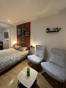 1 dormitorio con 1 cama, 2 sillas y mesa en Velours & Balnéo, en Saint-Nazaire