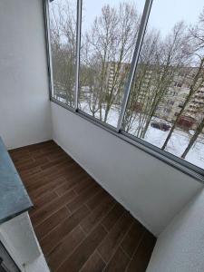 Habitación vacía con 2 ventanas grandes y suelo de madera. en Pleasant stay 1-bedroom apartment, en Šiauliai