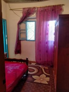 a bedroom with a bed and a window with pink curtains at New Oasis in Bawiti