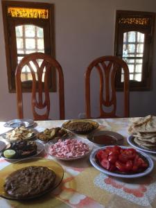 a table with plates of food on a table with chairs at New Oasis in Bawati