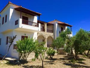 a large white house with trees in front of it at Gaia Apartments By Villa Kokkoni in Marathokampos