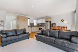 a living room with two leather couches and a kitchen at Nice & Quiet 2-Bed by Shops & Airport in Melbourne