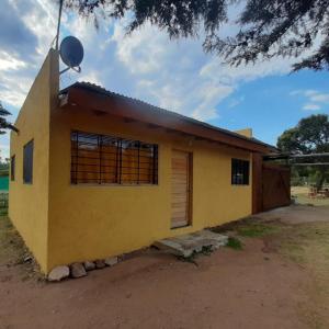 una casa amarilla con puerta y ventana en Aquellos Diaz- Cabaña con vista a las Sierras - Pileta - Wifi - Cochera techada - Aceptamos mascotas en Huerta Grande
