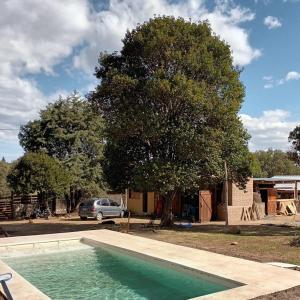 una piscina frente a una casa con un árbol en Aquellos Diaz- Cabaña con vista a las Sierras - Pileta - Wifi - Cochera techada - Aceptamos mascotas en Huerta Grande