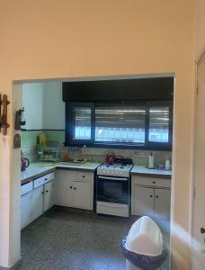 kuchnia z białymi szafkami, kuchenką i oknem w obiekcie Lo de Nenè hostal w mieście Cosquín