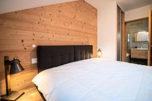 een slaapkamer met een groot bed en een houten muur bij Résidence LUMI BATIMENT B - Appartement LUMI B pour 4 Personnes 014 in Valmorel