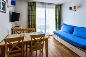 a living room with a blue couch and a table at Résidence Les Océanes - maeva Home - Studio 5 Personnes Confort - vue mer MAE-5816 in Pornichet