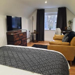 ein Schlafzimmer mit einem Bett und einem Sofa sowie einem Flachbild-TV in der Unterkunft Boundary House Studio, Moulton 