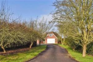 a road leading to a red barn with a white garage at Boundary House Studio, Moulton in Moulton