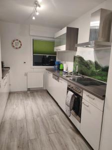 a kitchen with white appliances and a wooden floor at Modernes Rhombushaus mit Garten & Teich nähe Wald in Balve