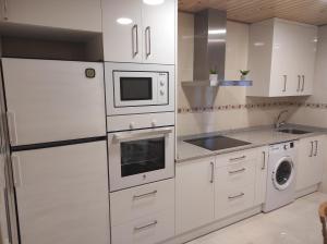 una cocina blanca con armarios y electrodomésticos blancos en Casa Rural La Maestra, 