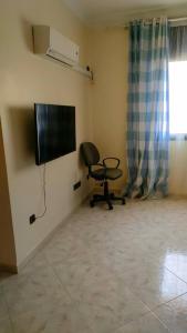 a room with a chair and a television on a wall at Logement calme très proche du centre in Oujda