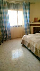 1 dormitorio con 1 cama, chimenea y ventana en Logement calme très proche du centre, en Oujda