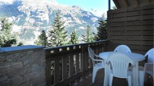 a patio with a table and chairs on a balcony with mountains at Les Chalets Petit Bonheur - Chalets pour 6 Personnes 484 in Villarodin-Bourget