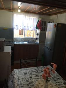 uma cozinha com uma mesa, um frigorífico e uma janela em Habitación cómoda por día em Valdivia