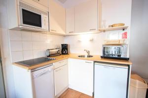 a small kitchen with white cabinets and a microwave at Les Chalets Petit Bonheur - Chalets pour 6 Personnes 504 in Villarodin-Bourget