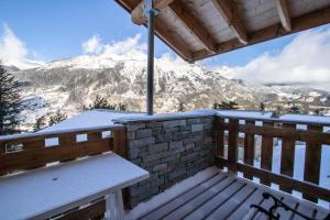 a bench on a balcony with a snow covered mountain at Les Chalets Petit Bonheur - Chalets pour 6 Personnes 504 in Villarodin-Bourget