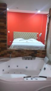 La salle de bains est pourvue d'une baignoire et d'un lit dans un miroir. dans l'établissement HOTEL EL CACIQUE POPAYAN, à Popayan