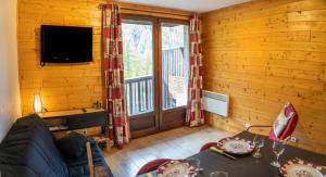 a living room with a couch and a table and a television at Résidence Les Ecrins - Studio pour 4 Personnes 224 in Les Orres