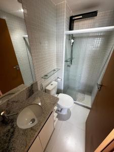 La salle de bains est pourvue d'un lavabo, de toilettes et d'une douche. dans l'établissement Studio Aconchegante com vista mar no Smart Pituba, à Salvador