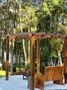 a wooden pergola with a bench in a park at Chácara Caminho das Águas in Piraquara