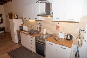 cocina con armarios blancos, fogones y nevera en Apartment Sasa, en Kaštela