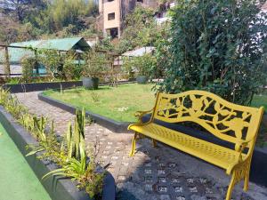a yellow bench sitting in a garden at Evergreen Suites Cozy Baguio Loft Retreat in Baguio