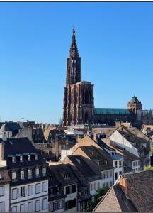 wysoka wieża zegarowa w mieście z budynkami w obiekcie La Rose w Strasburgu